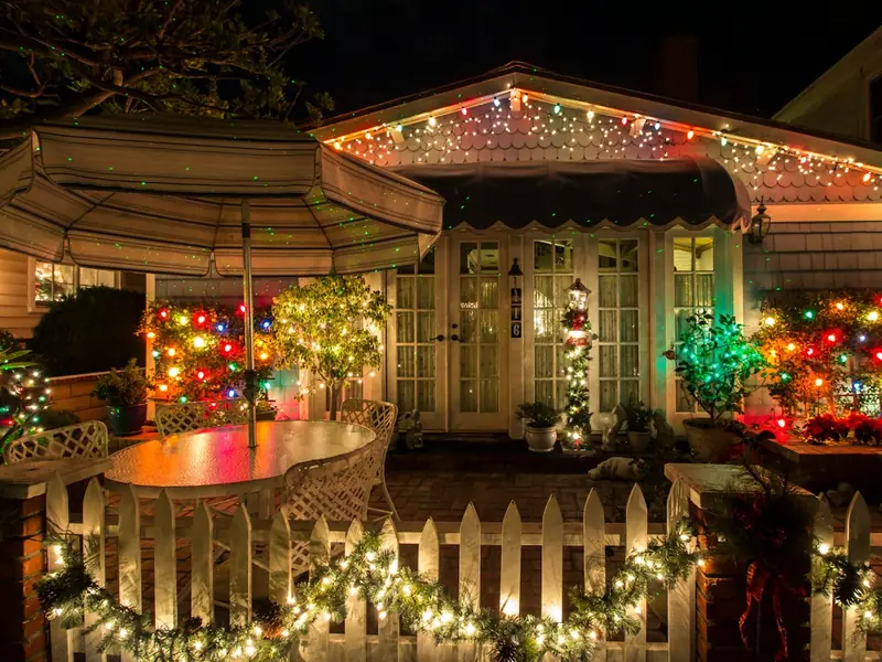 Porch railing and picket fence wrapped in lit garland