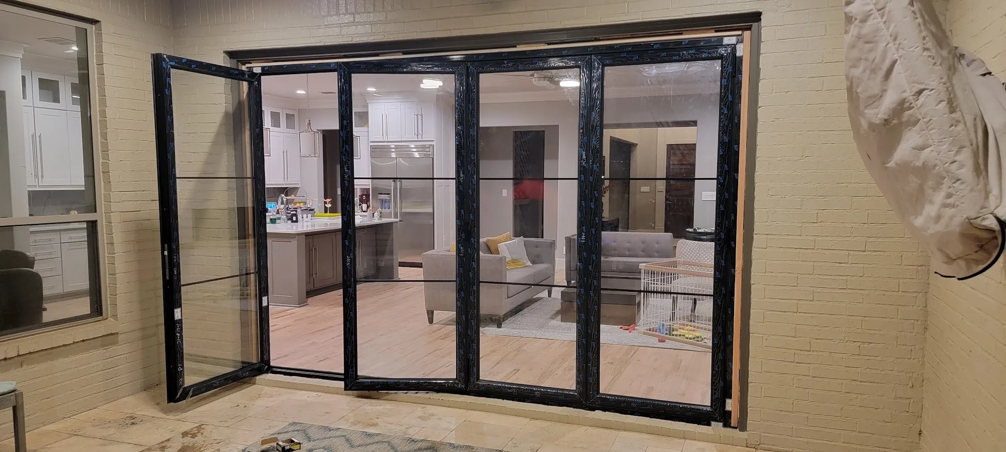 New black-framed panoramic 4-panel bifold patio door open to the kitchen and living room in a Twin Creeks home in Allen