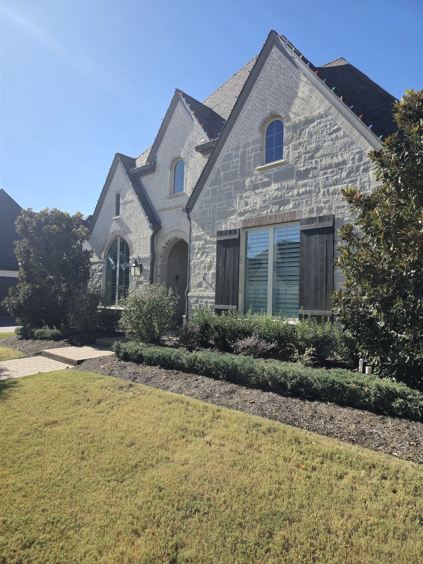 Front elevation of a gray stone European-style home in Watters Creek, Allen after a full 42-window Cardinal Low-E replacement