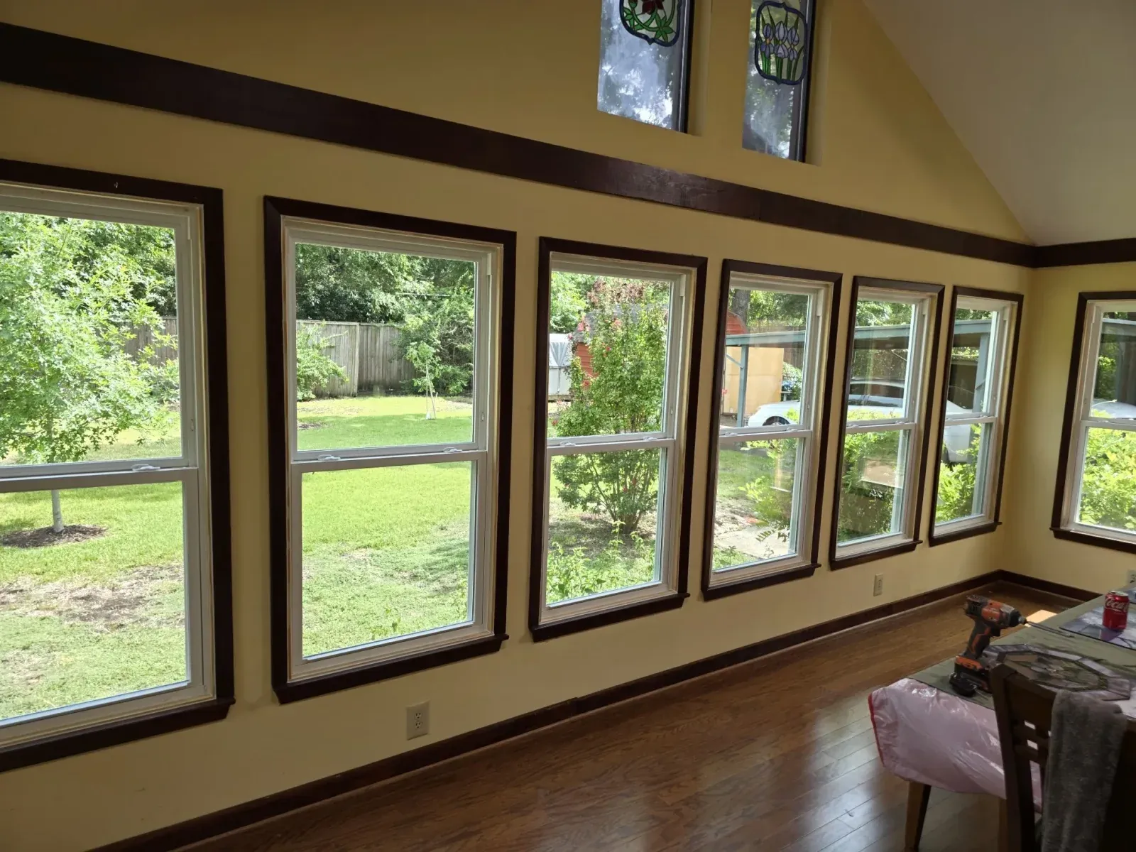Interior sunroom lined with new white Vistamark double-hung windows beneath stained-glass transoms in Historic Downtown McKinney