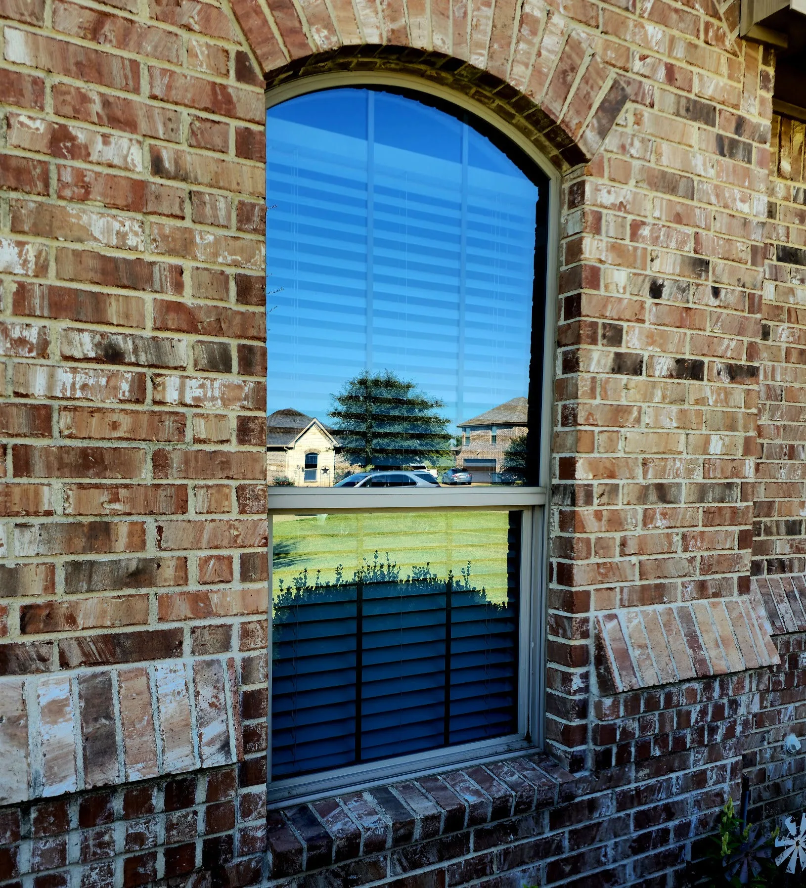 Arched-top window with laminated security glass on a CityLine brick home in North Richardson